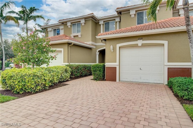 view of front of house featuring a garage, a tile roof, decorative driveway, and stucco siding