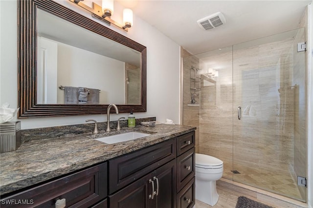 bathroom featuring toilet, vanity, and a shower with door