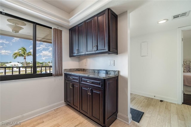 kitchen with dark brown cabinetry, crown molding, and light wood-type flooring