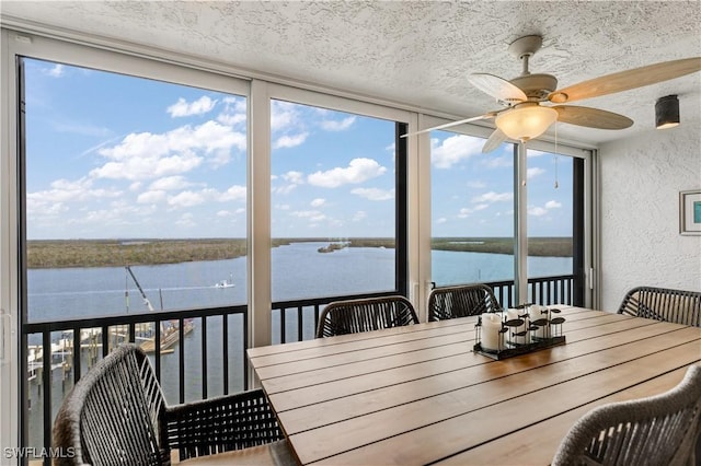 sunroom with ceiling fan, a healthy amount of sunlight, and a water view