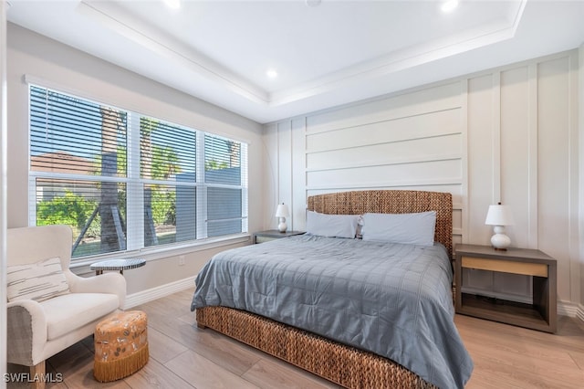 bedroom featuring a raised ceiling and light wood-type flooring