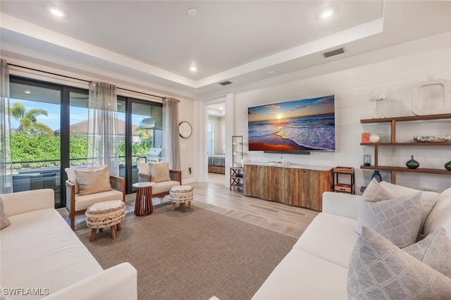 living room featuring a raised ceiling and light wood-type flooring