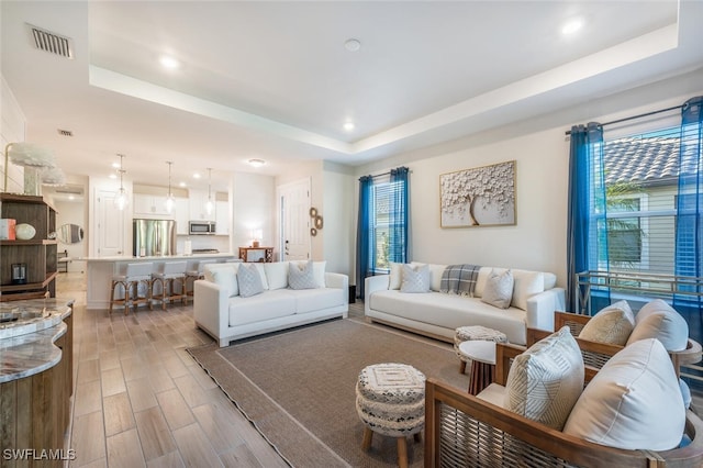 living room featuring a raised ceiling and plenty of natural light