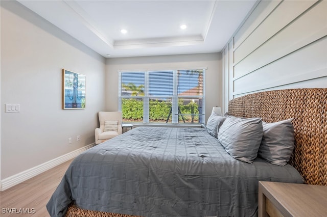 bedroom featuring light hardwood / wood-style floors and a raised ceiling