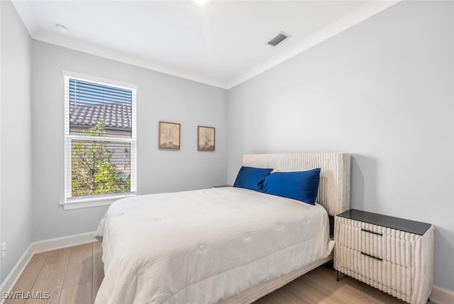 bedroom featuring crown molding and light hardwood / wood-style floors