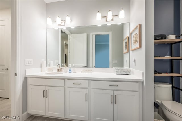 bathroom with toilet, hardwood / wood-style flooring, and vanity