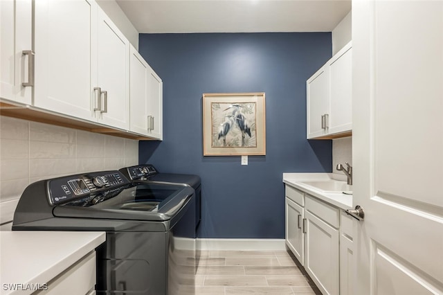 laundry area featuring cabinets, independent washer and dryer, and sink