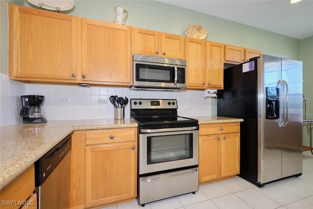 kitchen with tasteful backsplash, light tile patterned floors, light stone countertops, and stainless steel appliances