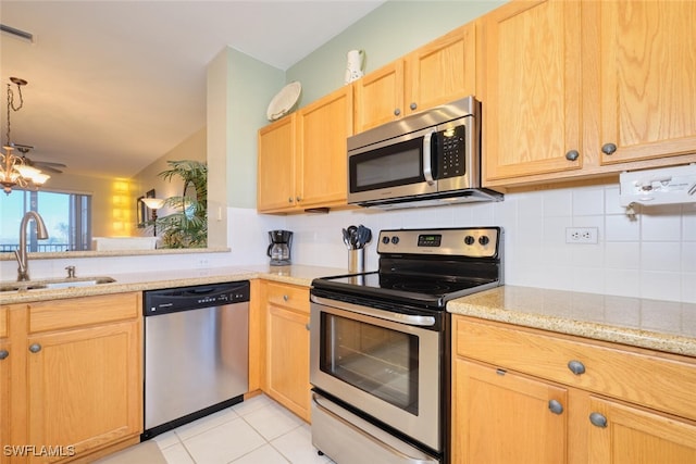 kitchen featuring light tile patterned floors, appliances with stainless steel finishes, lofted ceiling, light stone counters, and sink