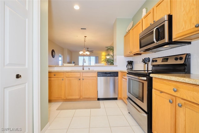 kitchen with an inviting chandelier, appliances with stainless steel finishes, light tile patterned flooring, hanging light fixtures, and sink