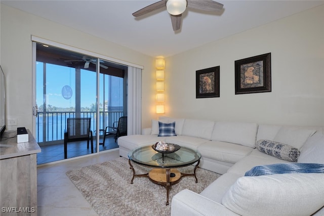 tiled living room with ceiling fan and a water view