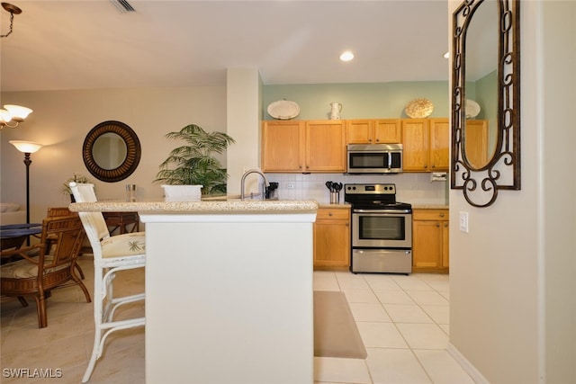 kitchen featuring appliances with stainless steel finishes, tasteful backsplash, sink, kitchen peninsula, and light tile patterned floors