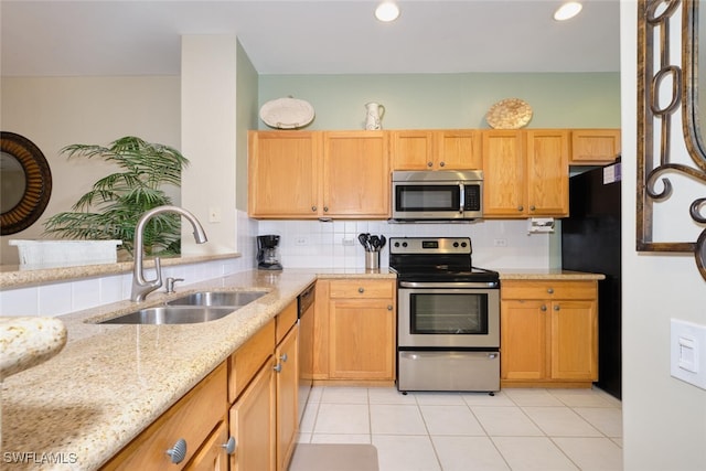 kitchen with light stone countertops, appliances with stainless steel finishes, decorative backsplash, sink, and light tile patterned flooring