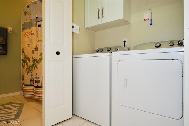 washroom with washing machine and dryer, cabinets, and light tile patterned floors