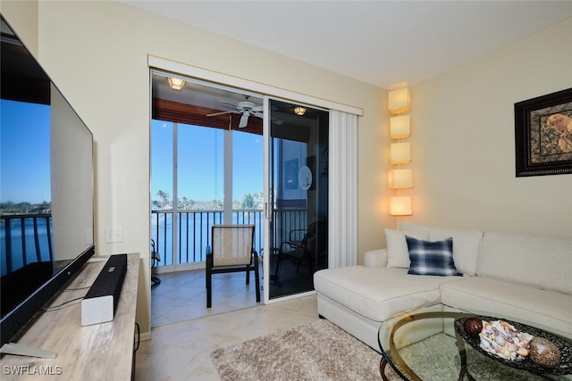 living room featuring ceiling fan and a water view