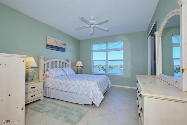 tiled bedroom with ceiling fan and a water view