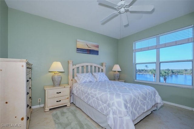 tiled bedroom with ceiling fan and a water view