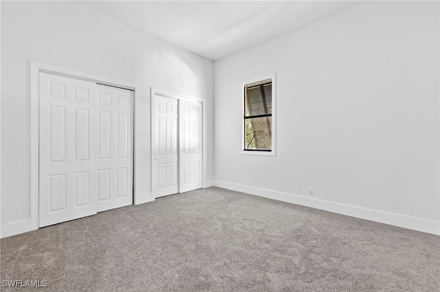 unfurnished bedroom featuring multiple closets and carpet floors