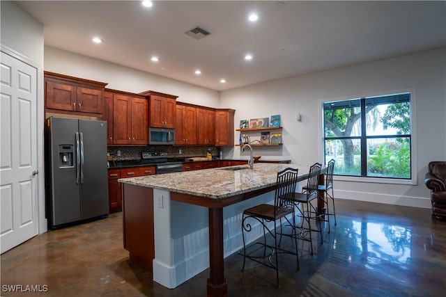 kitchen featuring sink, light stone countertops, an island with sink, a kitchen breakfast bar, and stainless steel appliances