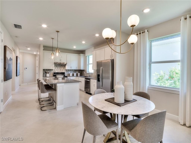 tiled dining area featuring sink, a notable chandelier, and a healthy amount of sunlight