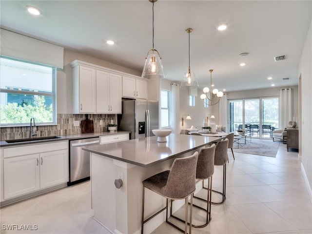 kitchen featuring stainless steel appliances, backsplash, hanging light fixtures, white cabinets, and sink