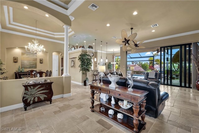 living room featuring ceiling fan with notable chandelier, a raised ceiling, ornamental molding, and ornate columns