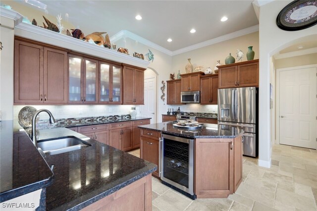 kitchen featuring beverage cooler, appliances with stainless steel finishes, a kitchen island, tasteful backsplash, and sink