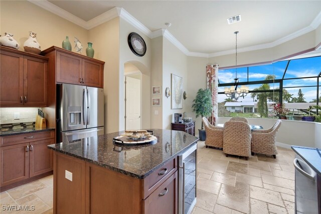 kitchen featuring stainless steel fridge, decorative light fixtures, dark stone counters, a kitchen island, and beverage cooler