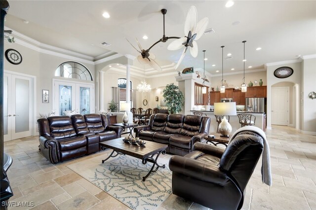 living room with a towering ceiling, french doors, crown molding, and an inviting chandelier