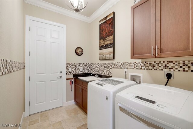 clothes washing area featuring crown molding, cabinets, sink, and washing machine and clothes dryer