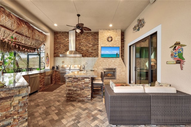 view of patio featuring a wet bar, exterior kitchen, an outdoor living space with a fireplace, and ceiling fan