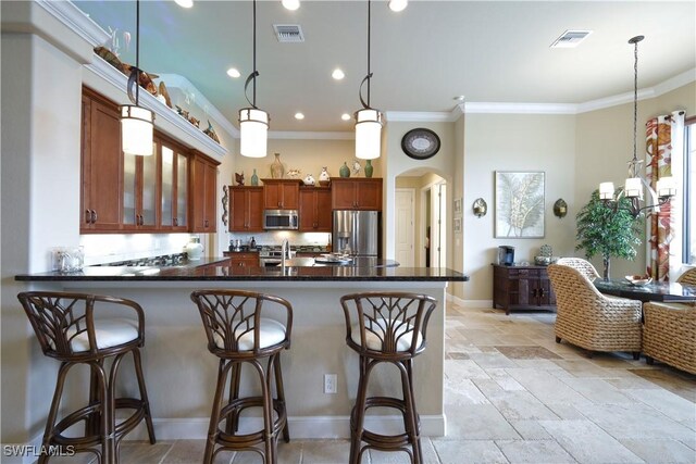 kitchen featuring hanging light fixtures, ornamental molding, kitchen peninsula, a breakfast bar, and stainless steel appliances