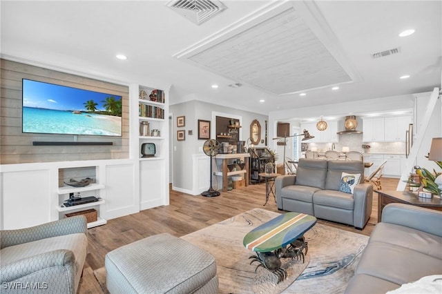 living room with built in shelves and light hardwood / wood-style floors