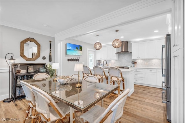 dining room featuring sink, crown molding, and light wood-type flooring