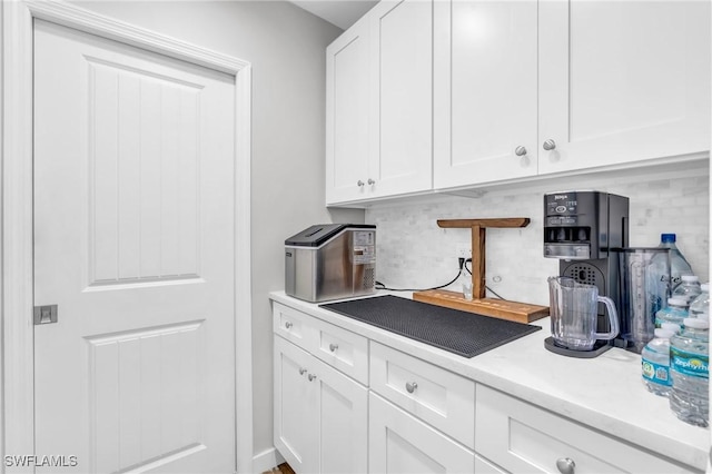 kitchen featuring white cabinetry, decorative backsplash, and light stone countertops