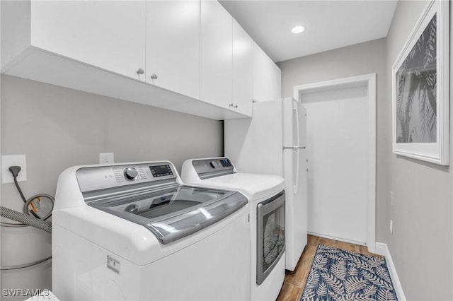 laundry area featuring cabinets, washer and clothes dryer, and wood-type flooring