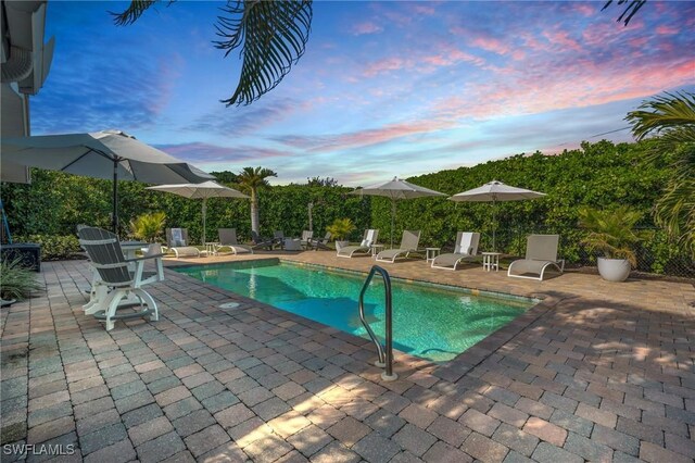 pool at dusk featuring a patio area