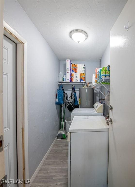 laundry area featuring water heater, wood-type flooring, and washing machine and dryer