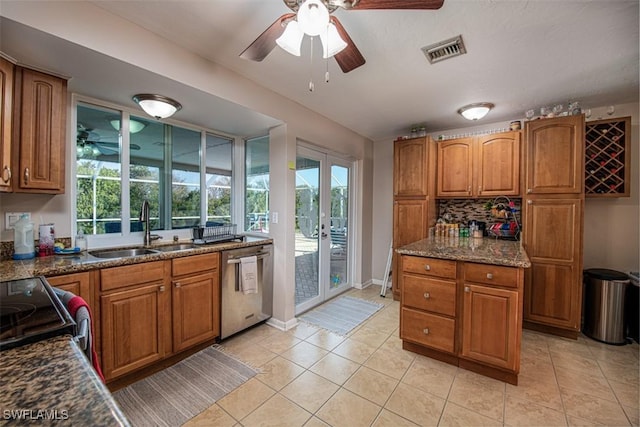 kitchen with light tile patterned floors, tasteful backsplash, dishwasher, dark stone counters, and sink