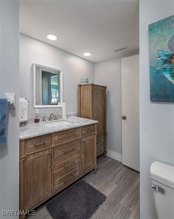 bathroom featuring toilet, vanity, and hardwood / wood-style floors