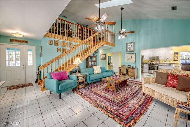 living room with ceiling fan, a high ceiling, light tile patterned floors, and sink