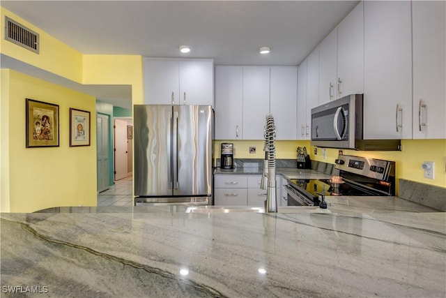 kitchen featuring white cabinets, light stone counters, and stainless steel appliances