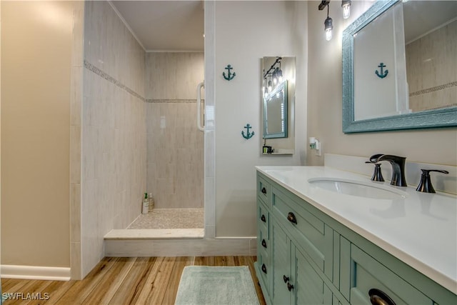 bathroom with wood-type flooring, tiled shower, and vanity