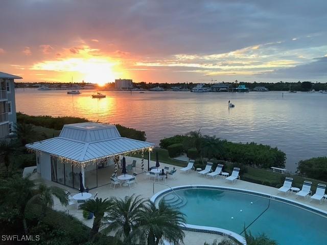 pool at dusk with a water view and a patio