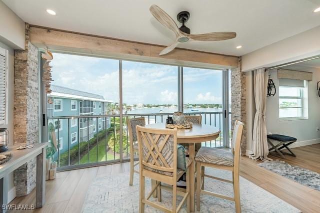 sunroom / solarium with a water view and ceiling fan