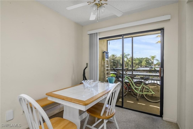 carpeted dining room with ceiling fan