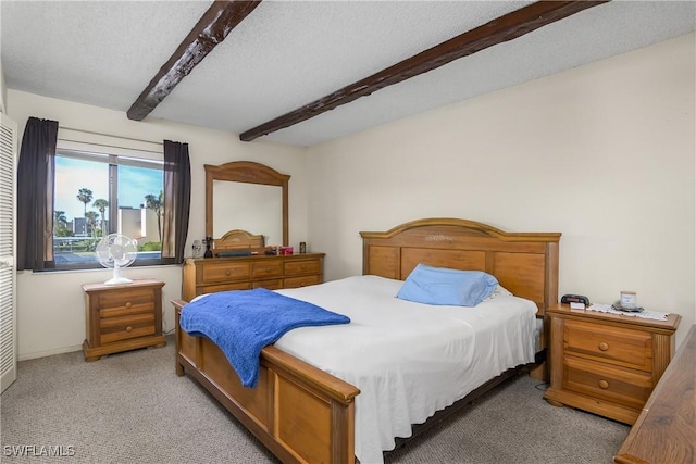 bedroom with beam ceiling, light colored carpet, and a textured ceiling