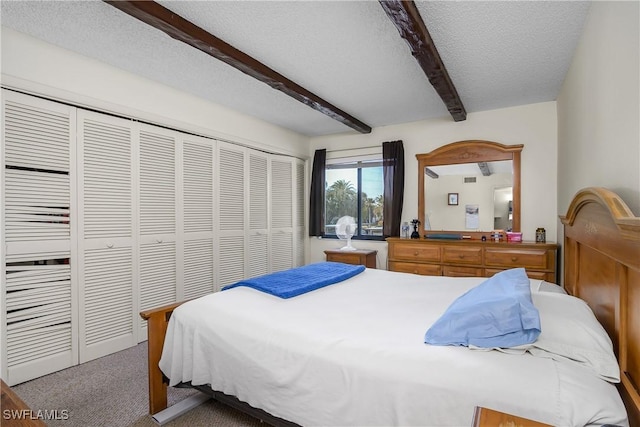 carpeted bedroom with beamed ceiling, a closet, and a textured ceiling