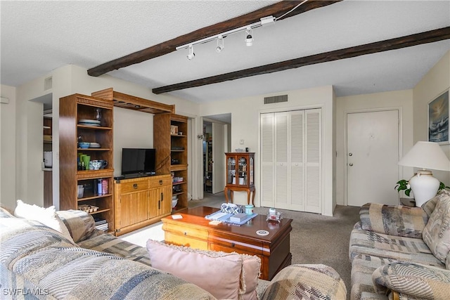 living room featuring beam ceiling, rail lighting, a textured ceiling, and carpet flooring