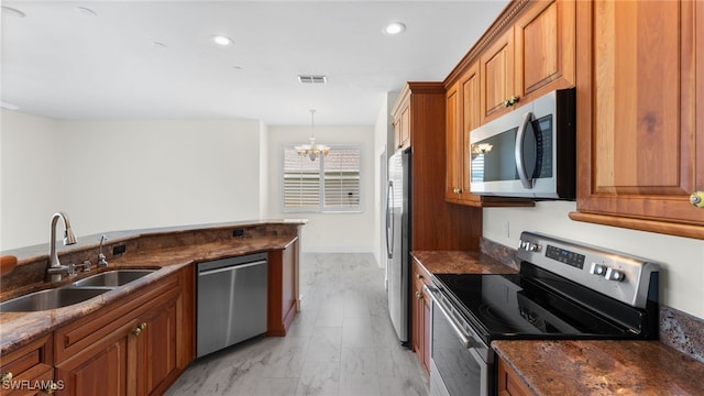 kitchen featuring decorative light fixtures, stainless steel appliances, dark stone countertops, an inviting chandelier, and sink